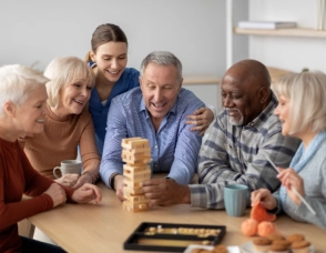 A group of senior people and a female caregiver playing together