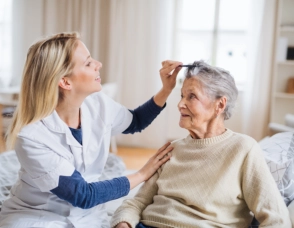 A female caregiver combing the hair of a senior woman