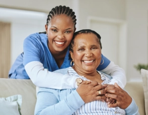 A senior woman sitting and a female caregiver hugging her