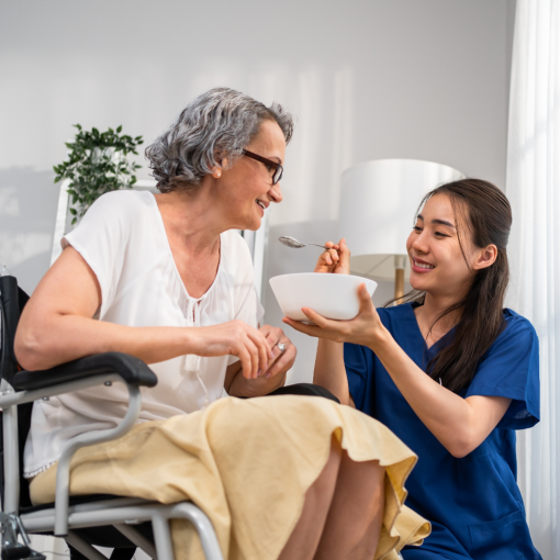 A female caregiver feeding a senior woman