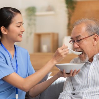 A female caregiver feeding a senior man