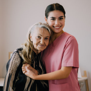 A senior woman and a female caregiver hugging each other