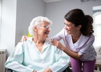 A female caregiver looking to a senior woman sitting on a wheelchair