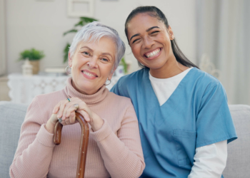 A senior woman and a female caregiver smiling