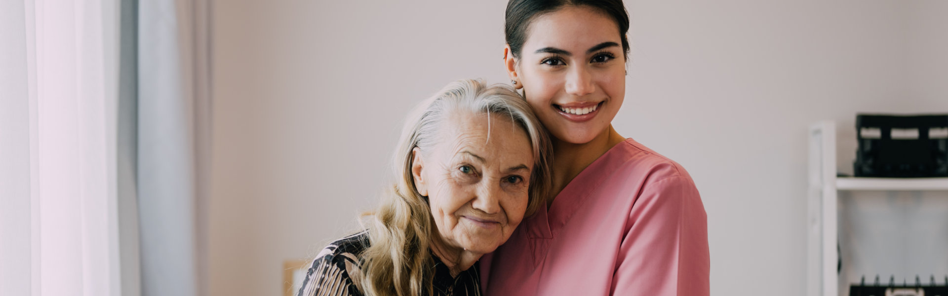 A senior woman and a female caregiver hugging each other