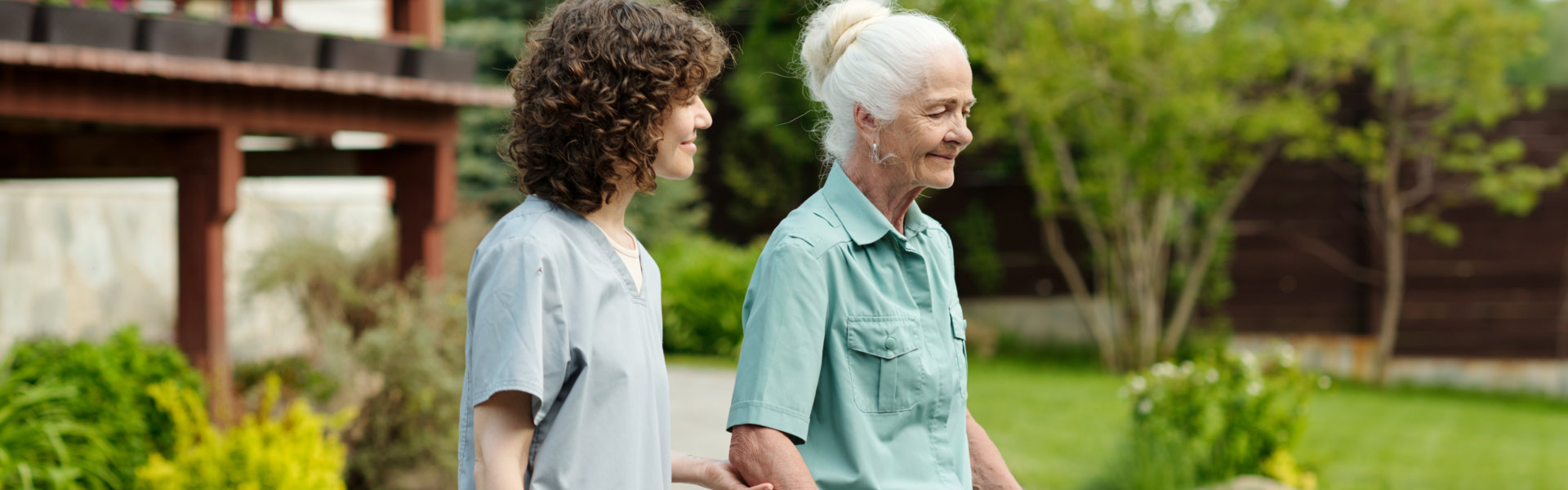 A female caregiver and a senior woman walking outside