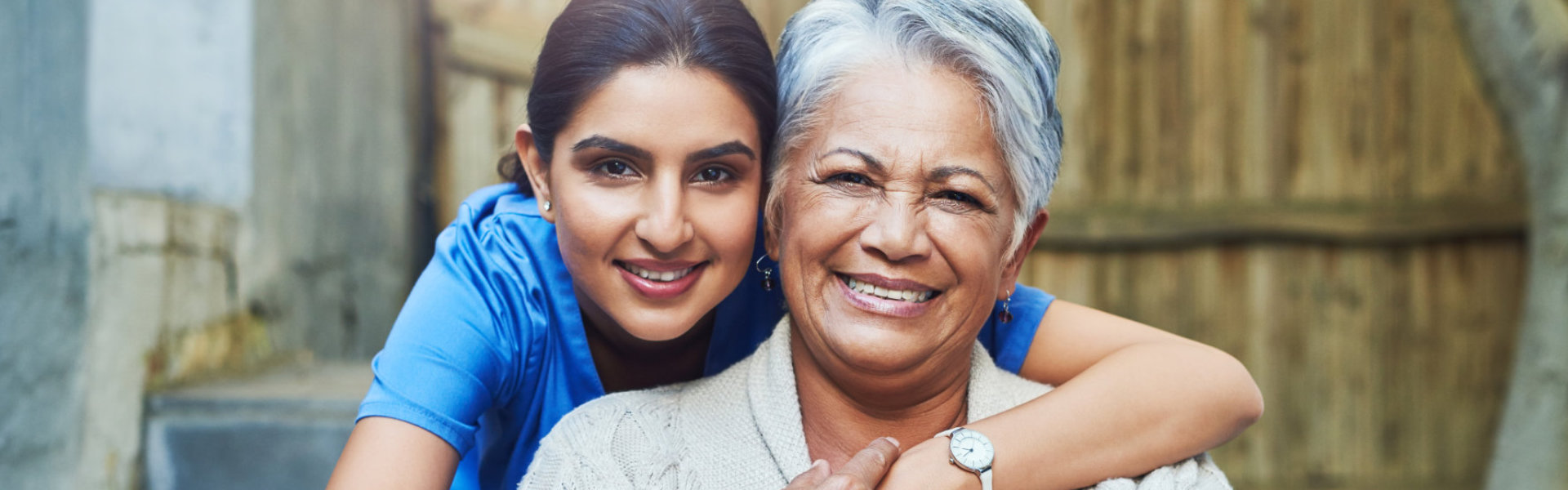 A female caregiver hugging the senior woman sitting on a wheelchair